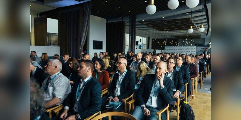 Audience of conference attendees seated in a presentation hall, used as illustrative startup-event imagery.