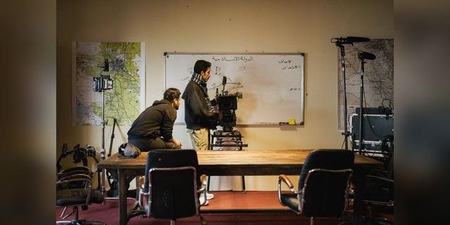 Two film crew members setting up a professional camera in a studio