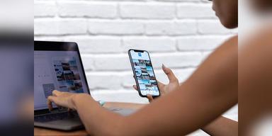 Woman using a laptop and smartphone for social-media work, used as illustrative creator-economy imagery.