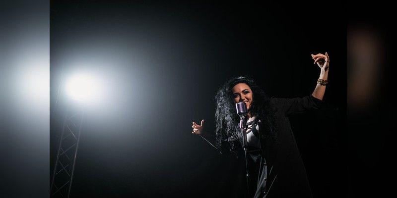 Female singer performing under a stage spotlight, used as illustrative live-music imagery.