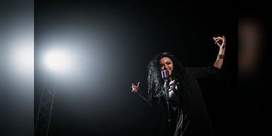Female singer performing under a stage spotlight, used as illustrative live-music imagery.
