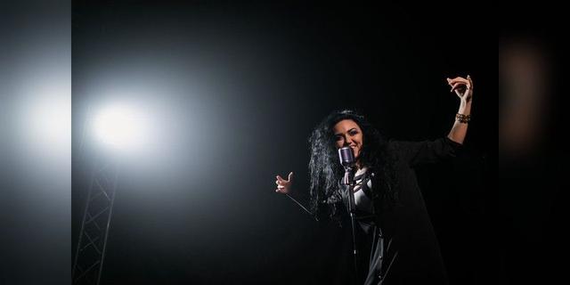 Female singer performing under a stage spotlight, used as illustrative live-music imagery.