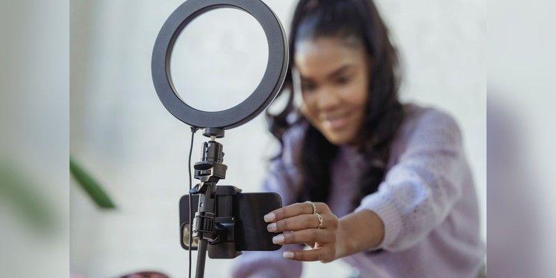 Creator setting up a smartphone on a tripod with a ring light for a video