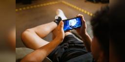 Adult playing a mobile video game on a smartphone, used as illustrative mobile-gaming imagery.