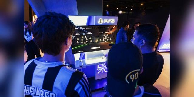 Gamers gathered around a football game selection screen at a PS5 event, used as illustrative gaming-event imagery.