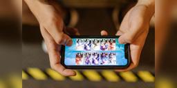 Hands playing a mobile game on a smartphone, used as illustrative mobile-esports imagery.