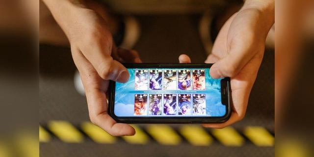 Hands playing a mobile game on a smartphone, used as illustrative mobile-esports imagery.