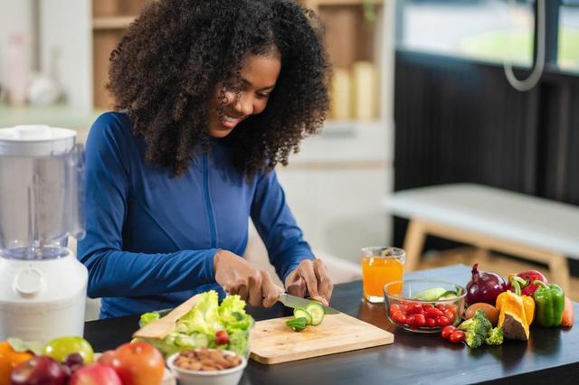 Person working at a tidy desk with water, healthy food, planner and laptop, symbolising balanced routines, mindfulness, exercise and productivity habits in a modern workspace.