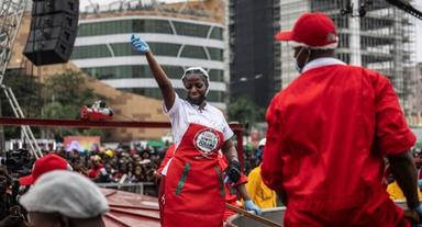 Hilda Baci cooking in a giant six-metre-wide pot of Jollof rice during her Guinness World Record attempt, with supporters and dignitaries around her.