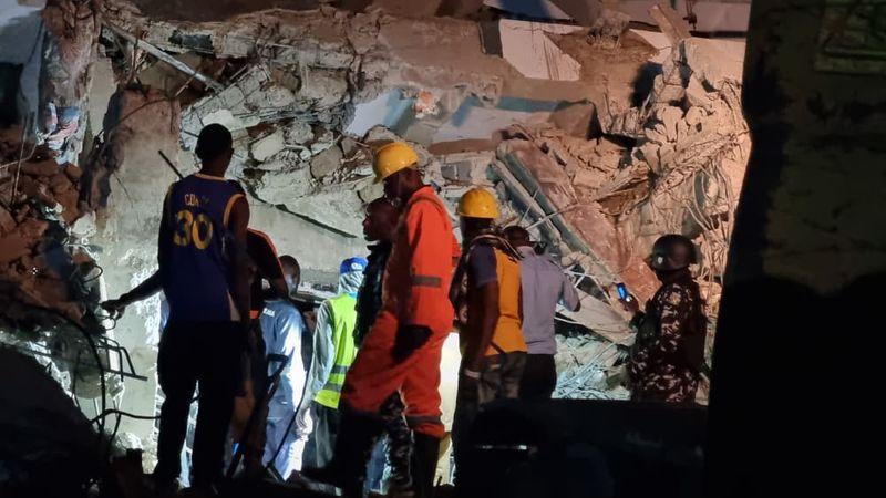 Rescue workers search through rubble of collapsed three-storey building on Borno Street, Yaba, Lagos, at night with emergency lights and equipment.