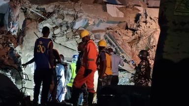 Rescue workers search through rubble of collapsed three-storey building on Borno Street, Yaba, Lagos, at night with emergency lights and equipment.