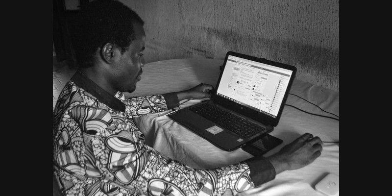 An African professional working on a laptop computer in an office environment.