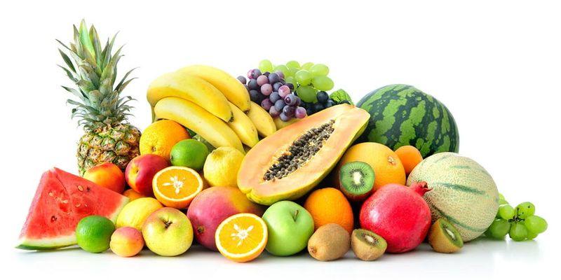 A colourful selection of fresh Nigerian fruits including bananas, oranges, watermelon, pineapple, pawpaw and mangoes displayed at a local market.