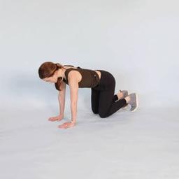 Person performing gentle lower back stretches on a yoga mat in a bright living room.
