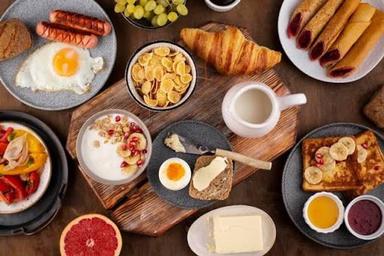 Healthy breakfast spread featuring oatmeal, fruit smoothie, avocado toast, boiled eggs, yoghurt and fresh fruits on a kitchen table.