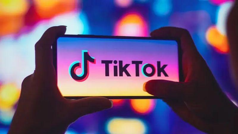 TikTok logo superimposed over an image of a smartphone displaying the app, symbolizing content moderation efforts.
