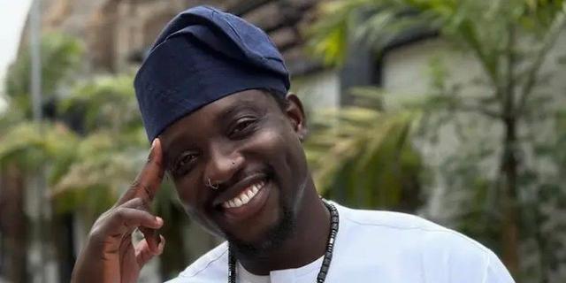Nigerian social media activist VeryDarkMan (Martins Otse) smiling, wearing a white outfit and navy cap