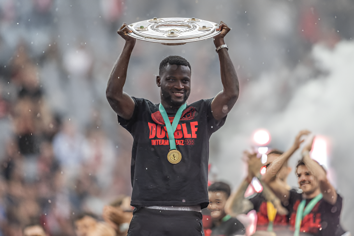 Nigerian star, Victor Boniface proudly holding the Bundelisga trophy plate above his head while wearing his medal