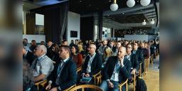 Audience of conference attendees seated in a presentation hall, used as illustrative startup-event imagery.