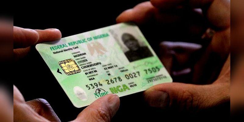 A Nigerian National Identity Number card held against a blurred background.