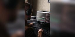 Software developer working at a desk with code on monitors, used as illustrative digital-infrastructure imagery.