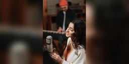 Singer using a studio microphone while a musician plays keyboard, used as illustrative music-production imagery.