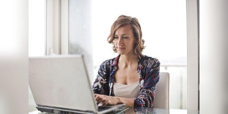 Woman working on a laptop in a bright home office, used as illustrative home-internet imagery.