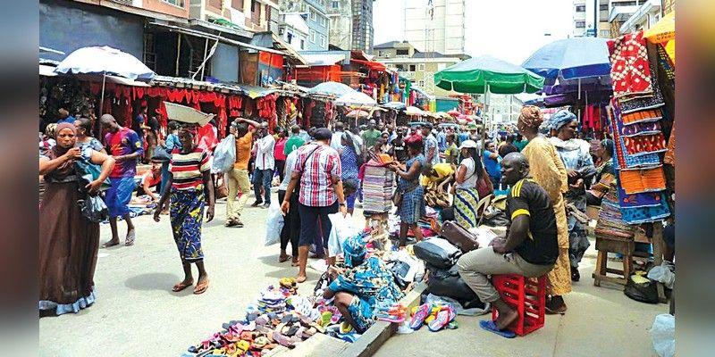 Shoppers and traders move through a busy open market in Lagos.