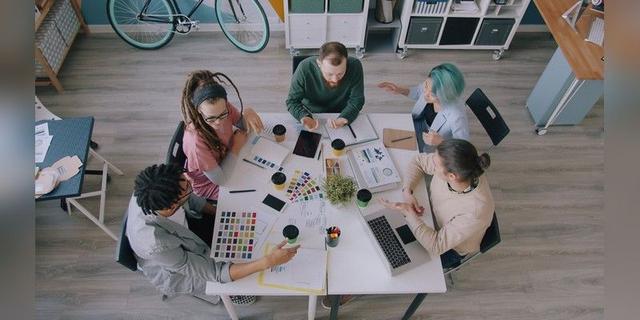 Creative team collaborating around a table, used as illustrative creative-partnership imagery.