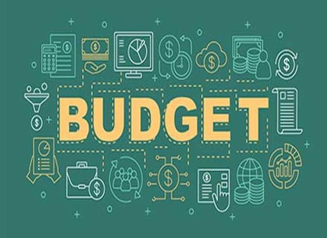 A Nigerian woman reviewing her monthly budget and expenses on a laptop while calculating savings and household costs amid rising living expenses.