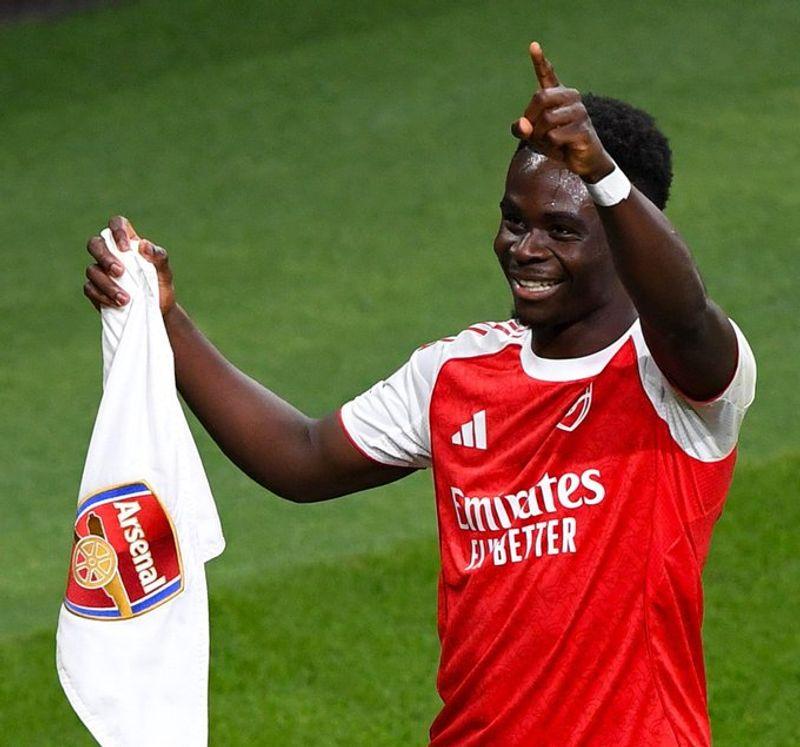 Bukayo Saka celebrating with Arsenal teammates after winning the Premier League title at London Colney training ground.