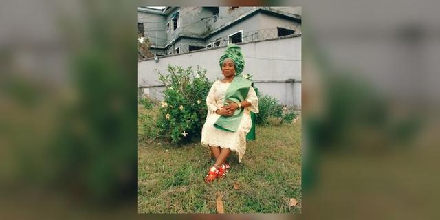 A woman wearing coordinated green-and-cream Àṣọ Ẹbí style clothing and colourful adidas sneakers at an outdoor celebration setting.
