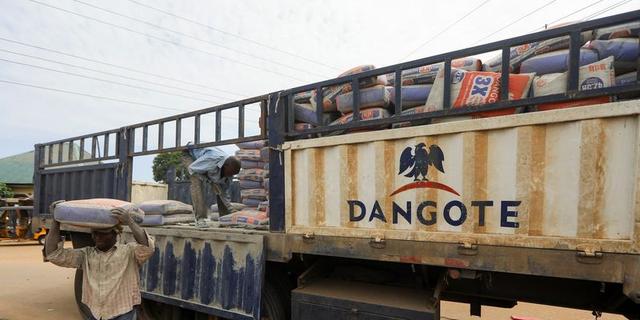 A worker carries a bag of cement from a truck loaded with cement bags in Nigeria.