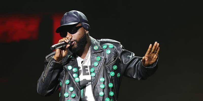 Davido performing on stage in a studded leather jacket and cap at a concert in Los Angeles