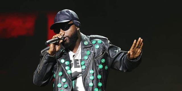 Davido performing on stage in a studded leather jacket and cap at a concert in Los Angeles