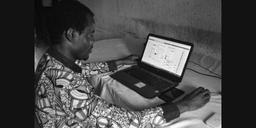 An African professional working on a laptop computer in an office environment.