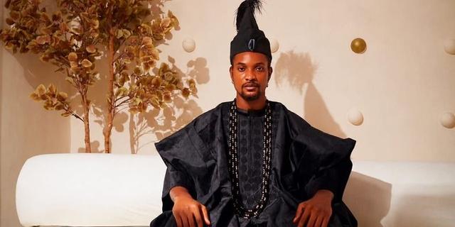 A Nigerian man wears black traditional-inspired menswear in an editorial portrait.