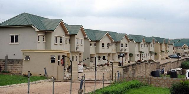 A row of multi-storey residential homes with green roofs in Abuja.